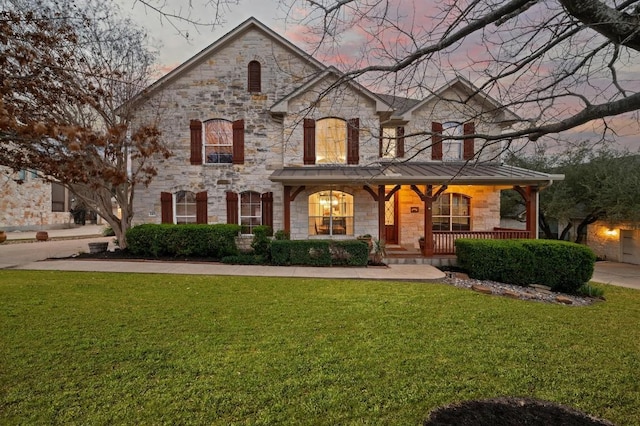 view of front of property featuring covered porch and a yard