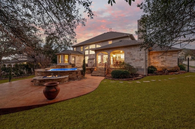 back house at dusk with a patio, a lawn, and a fenced in pool