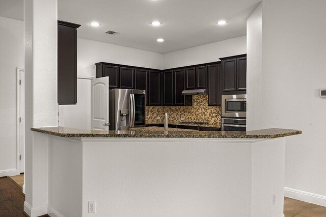 578 Ledge Stone Dr, Austin, TX 78737 - kitchen with stainless steel appliances, dark stone counters, decorative backsplash, baseboards, and recessed lighting