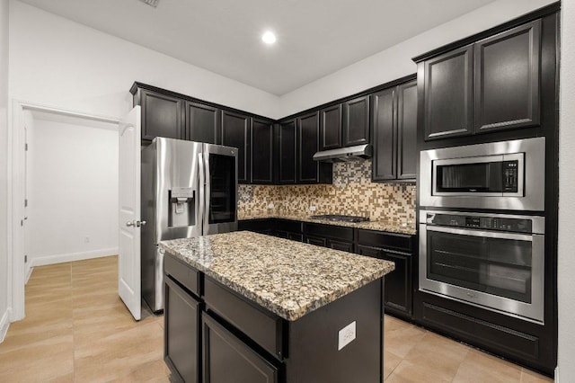 578 Ledge Stone Dr, Austin, TX 78737 - kitchen with appliances with stainless steel finishes, a center island, light stone countertops, under cabinet range hood, and decorative backsplash