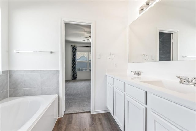 bathroom featuring a tub, vanity, ceiling fan, and wood-type flooring