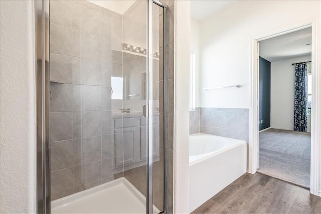 bathroom with hardwood / wood-style flooring and shower with separate bathtub