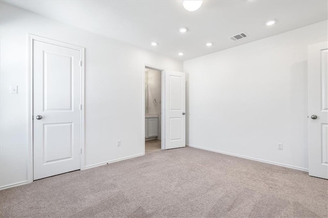 unfurnished bedroom featuring ensuite bath and light colored carpet