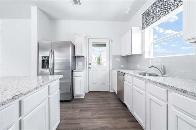 kitchen with stainless steel appliances, light stone countertops, white cabinets, decorative backsplash, and sink