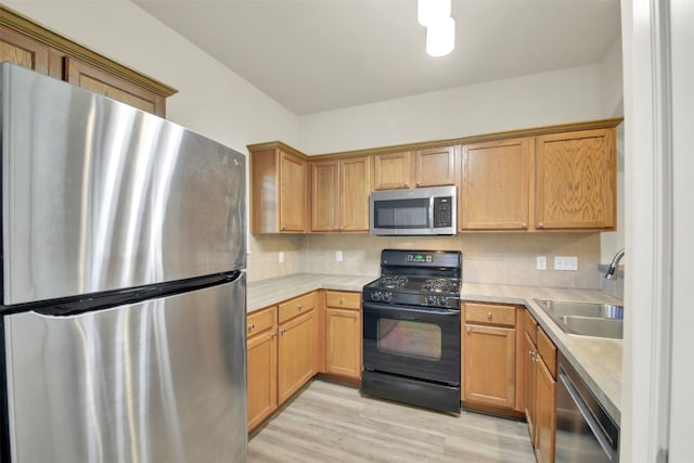 kitchen with sink, appliances with stainless steel finishes, tasteful backsplash, and light hardwood / wood-style flooring