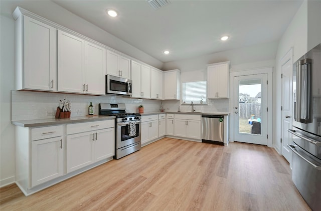 kitchen featuring sink, appliances with stainless steel finishes, white cabinets, and light hardwood / wood-style floors