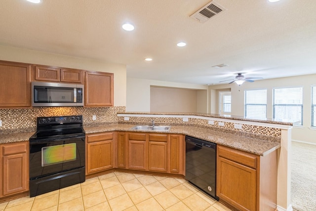 kitchen with light tile patterned floors, sink, black appliances, kitchen peninsula, and tasteful backsplash