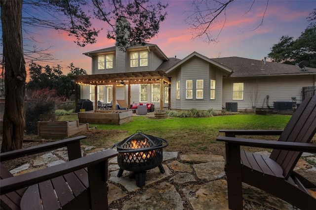 back house at dusk featuring a yard, a pergola, an outdoor fire pit, and a patio area