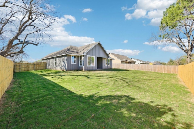back of house featuring a fenced backyard, board and batten siding, and a yard