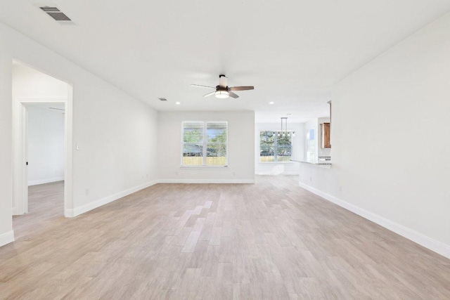 spare room with light wood-type flooring, baseboards, ceiling fan with notable chandelier, visible vents, and recessed lighting