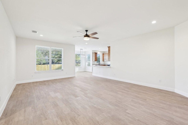 unfurnished living room with baseboards, ceiling fan, and light wood-type flooring