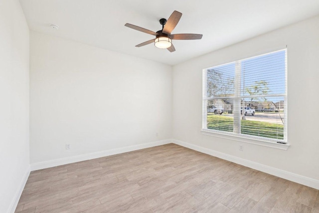 empty room featuring a ceiling fan, baseboards, and light wood-type flooring