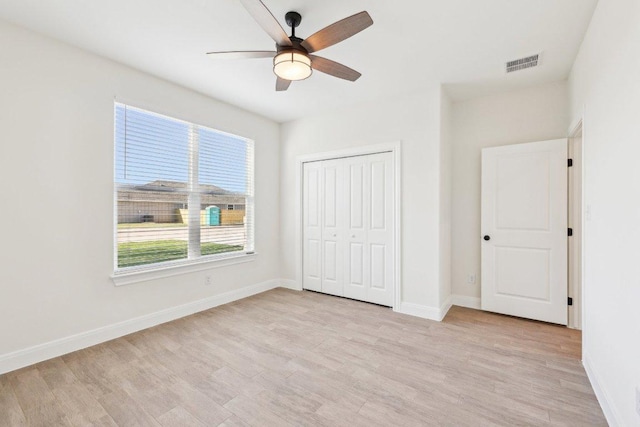 unfurnished bedroom featuring baseboards, light wood-style flooring, visible vents, and a closet