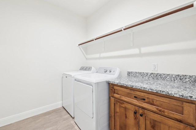 washroom featuring baseboards, light wood-style flooring, laundry area, and separate washer and dryer