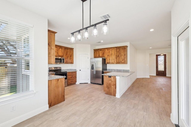 kitchen featuring a peninsula, stainless steel appliances, and brown cabinets