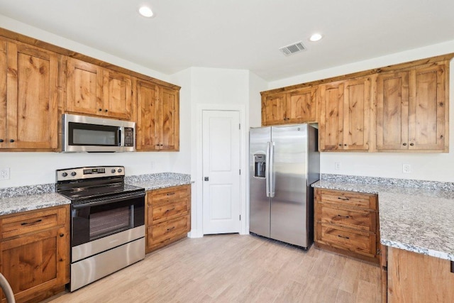 kitchen featuring visible vents, light wood-style floors, brown cabinets, and appliances with stainless steel finishes