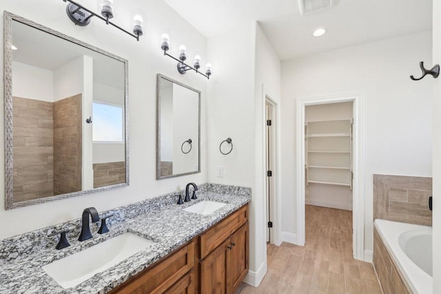 bathroom featuring visible vents, a sink, a spacious closet, and a washtub