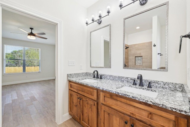 bathroom with double vanity, a sink, tiled shower, and a ceiling fan