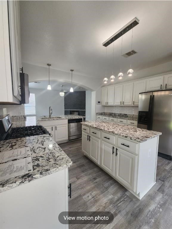 2500 National Park Blvd, Austin, TX 78747 - kitchen featuring appliances with stainless steel finishes, wood finished floors, white cabinets, light stone counters, and a peninsula