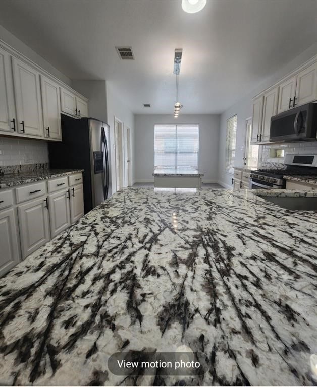 2500 National Park Blvd, Austin, TX 78747 - kitchen with stainless steel appliances, light stone counters, tasteful backsplash, and white cabinets