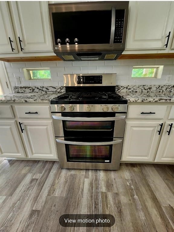 2500 National Park Blvd, Austin, TX 78747 - kitchen featuring appliances with stainless steel finishes, white cabinets, light wood-style flooring, and light stone counters