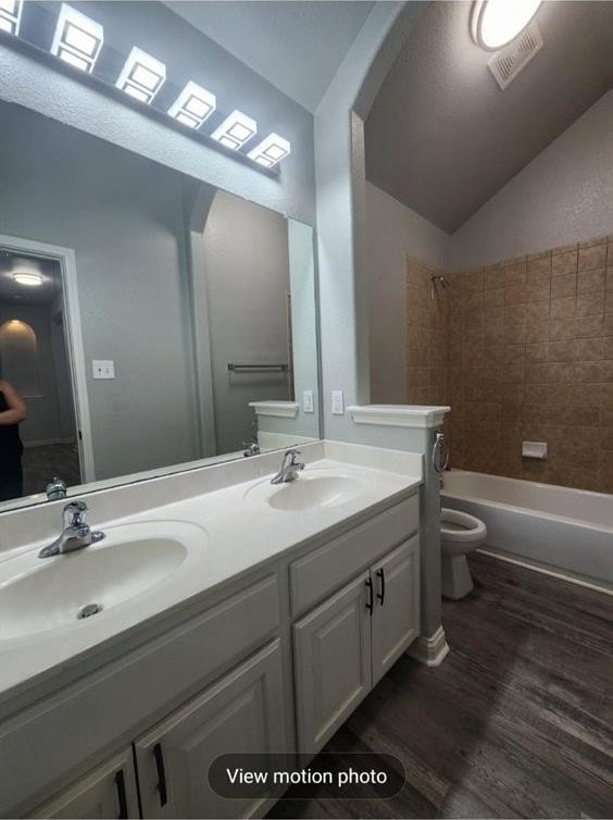 2500 National Park Blvd, Austin, TX 78747 - bathroom with double vanity, wood finished floors, lofted ceiling, and shower / bathtub combination