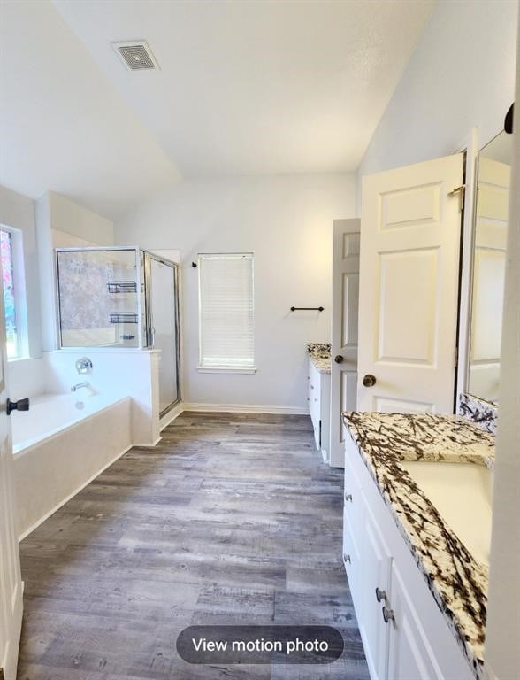 2500 National Park Blvd, Austin, TX 78747 - bathroom with vaulted ceiling, two vanities, a garden tub, a stall shower, and wood finished floors