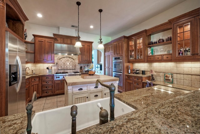 kitchen featuring hanging light fixtures, light tile patterned floors, stainless steel appliances, and decorative backsplash