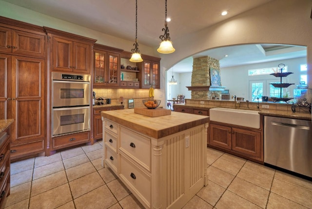 kitchen featuring a center island, butcher block countertops, sink, backsplash, and appliances with stainless steel finishes