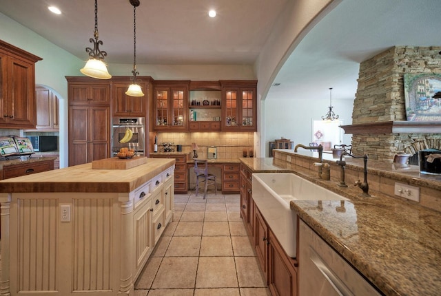 kitchen featuring sink, a center island, pendant lighting, wooden counters, and tasteful backsplash