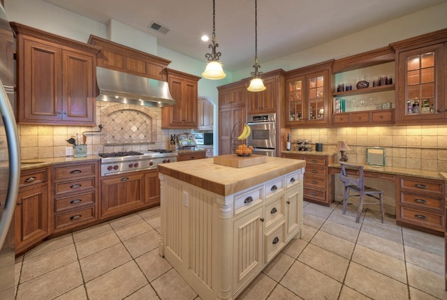 kitchen featuring backsplash, a kitchen island, decorative light fixtures, stainless steel appliances, and ventilation hood