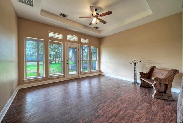 unfurnished room featuring a raised ceiling, ceiling fan, and dark wood-type flooring