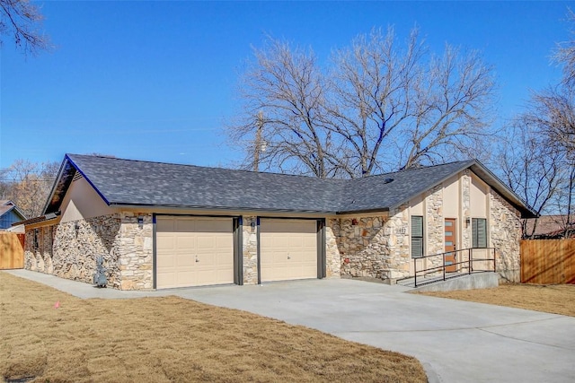 view of front of home with a garage, stone siding, roof with shingles, fence, and a front lawn