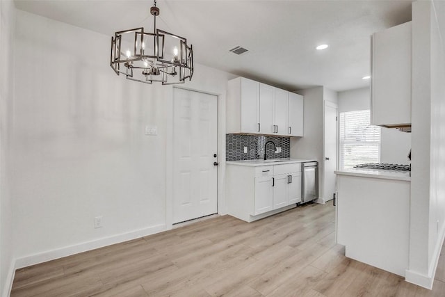 1402 Valleyridge Cir, Austin, TX 78704 - kitchen with stainless steel appliances, a chandelier, light wood-style floors, backsplash, and white cabinetry