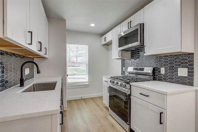 1402 Valleyridge Cir, Austin, TX 78704 - kitchen featuring appliances with stainless steel finishes, light wood-type flooring, backsplash, white cabinetry, and recessed lighting