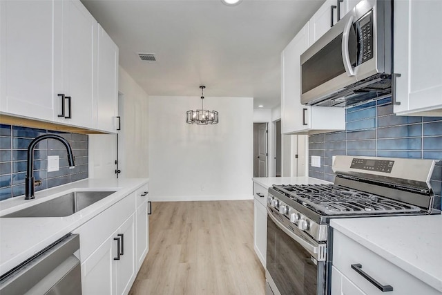 1402 Valleyridge Cir, Austin, TX 78704 - kitchen featuring appliances with stainless steel finishes, decorative backsplash, a chandelier, white cabinetry, and recessed lighting