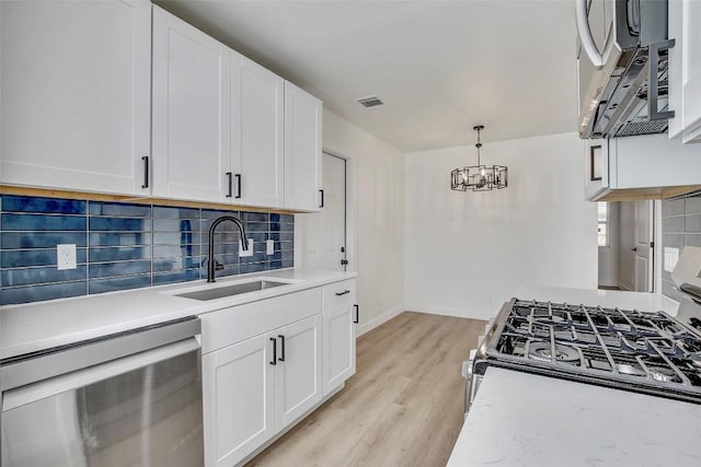 1402 Valleyridge Cir, Austin, TX 78704 - kitchen with stainless steel appliances, a chandelier, light wood-style flooring, decorative backsplash, and light countertops