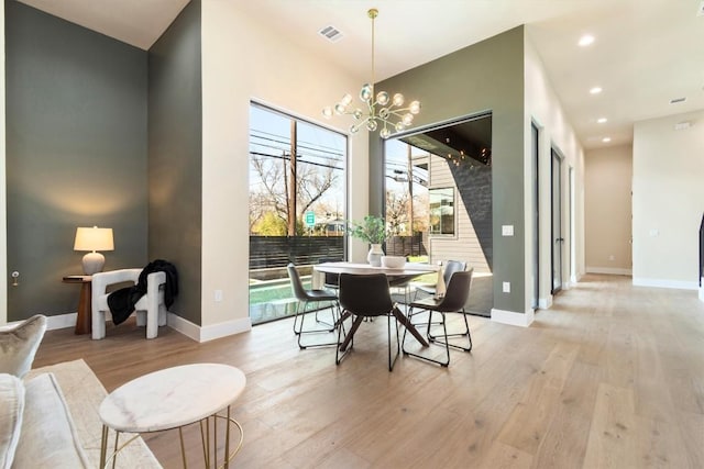 dining space with light wood finished floors, visible vents, and baseboards