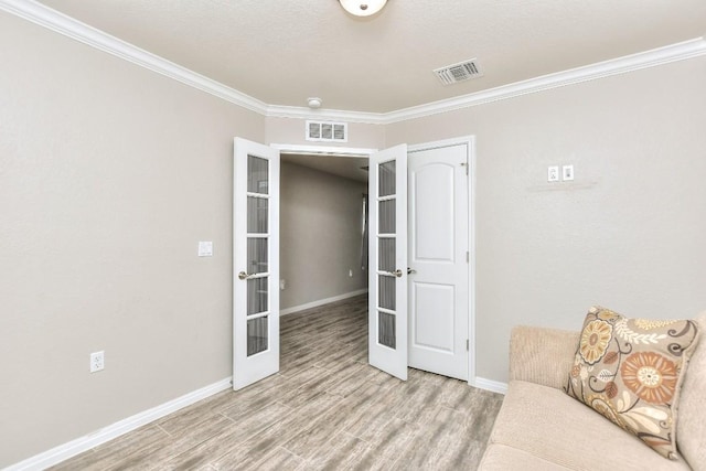 living area with light wood-type flooring, french doors, and ornamental molding