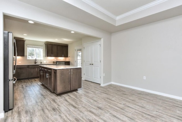 kitchen with a kitchen island, dark brown cabinetry, stainless steel fridge, and light hardwood / wood-style flooring