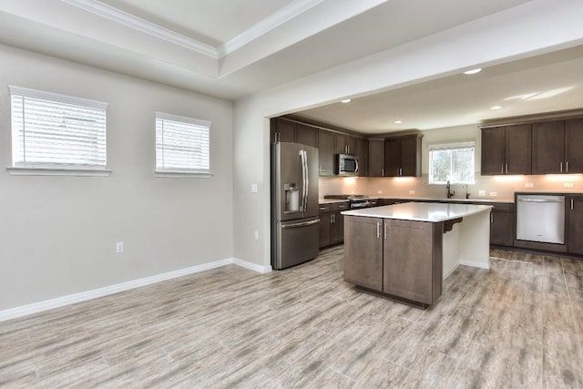 kitchen featuring appliances with stainless steel finishes, light wood-type flooring, dark brown cabinetry, a kitchen island, and sink