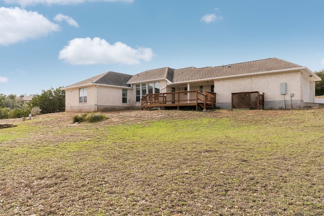 rear view of house featuring a lawn and a deck