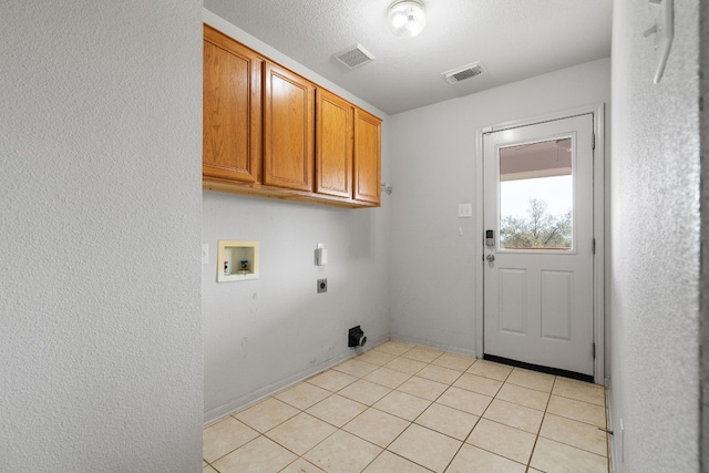 clothes washing area featuring a textured ceiling, hookup for a washing machine, electric dryer hookup, light tile patterned floors, and cabinets