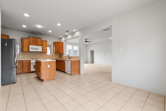 kitchen featuring a kitchen island, sink, white appliances, ceiling fan, and light tile patterned floors