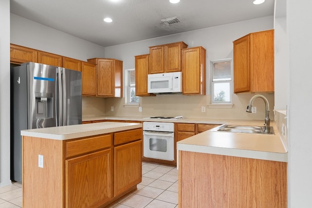 kitchen featuring sink, white appliances, a center island, and light tile patterned floors