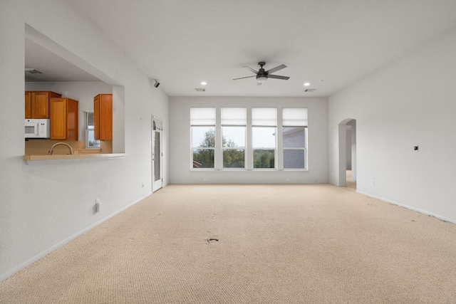 unfurnished living room featuring ceiling fan and light colored carpet