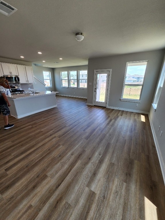 unfurnished living room featuring a textured ceiling and dark hardwood / wood-style floors