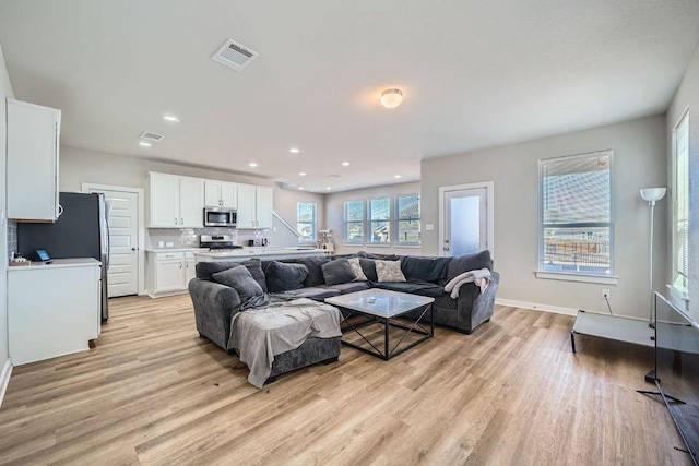 living room with light wood finished floors, baseboards, visible vents, and recessed lighting