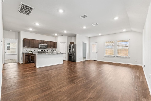 kitchen featuring a center island with sink, stainless steel appliances, dark wood-type flooring, and decorative backsplash