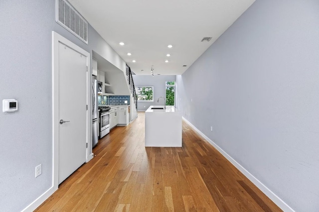 2002 E 7th St Unit 204, Austin, TX 78702 - kitchen with stainless steel range with gas stovetop, light wood-style floors, backsplash, recessed lighting, and light countertops